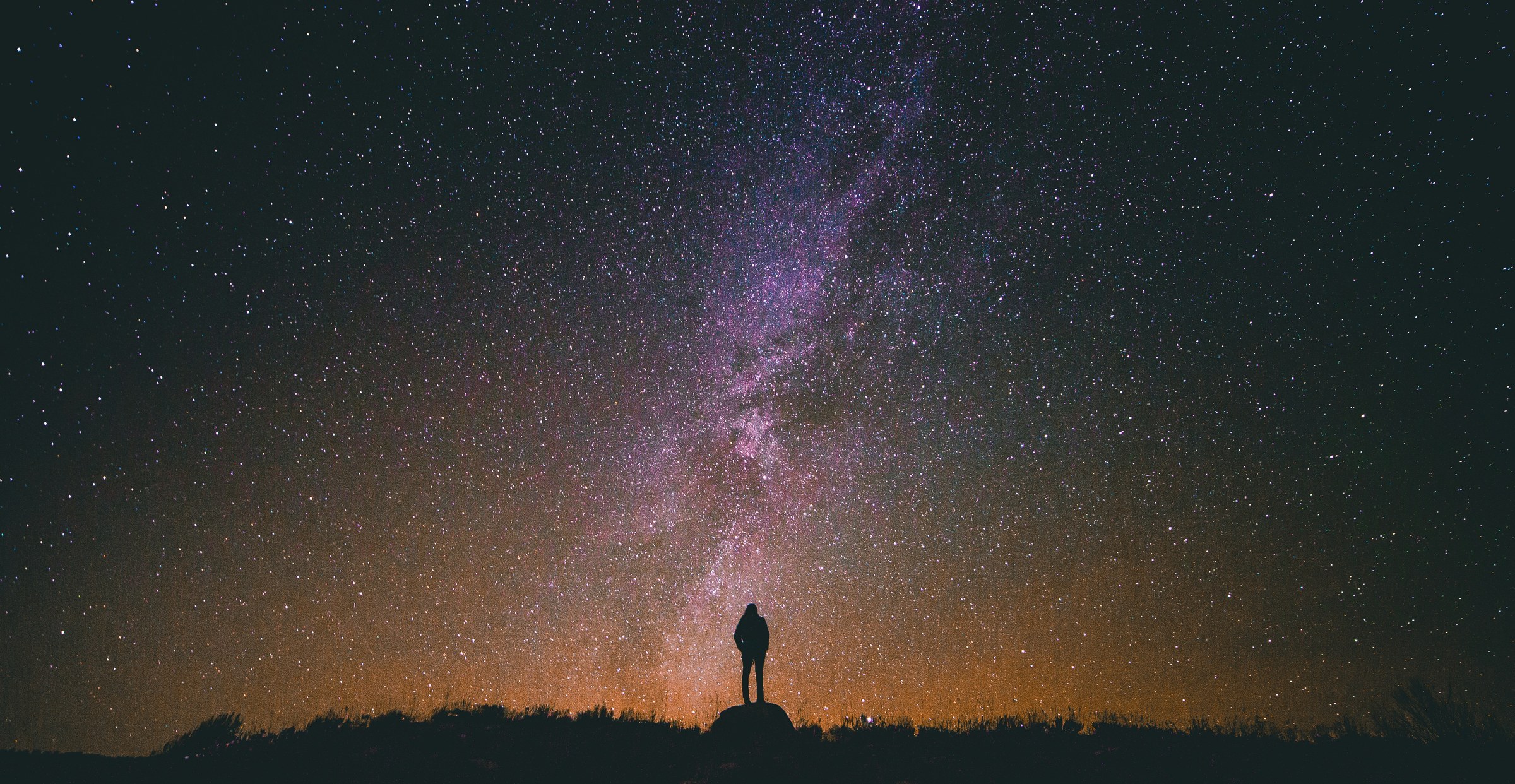 Silhouette beneath the Milky Way — a figure standing in cosmic vastness